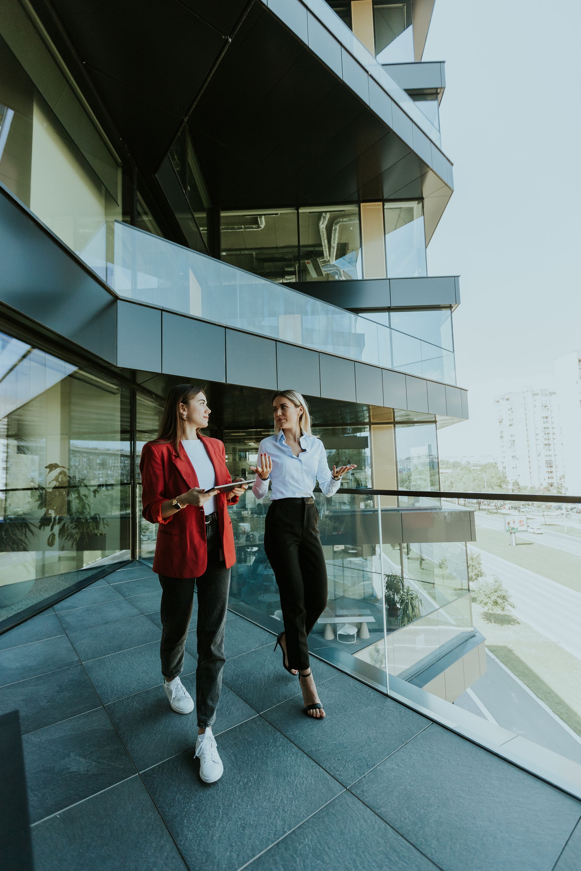 Two businesswomen discussing strategy outside a modern office building